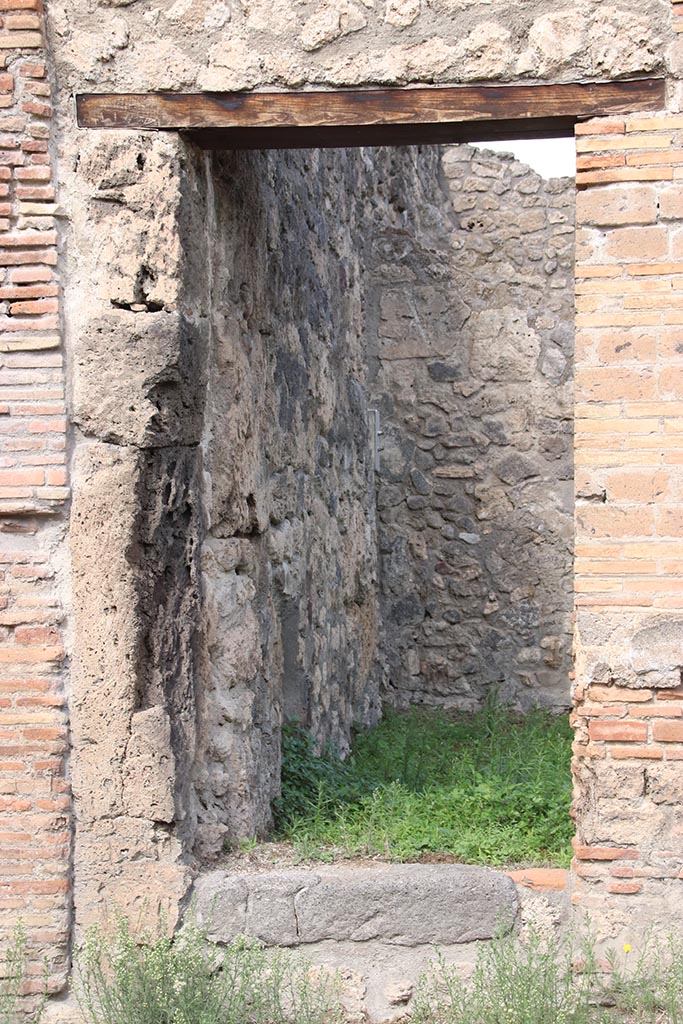 I.2.26 Pompeii. October 2024.
Looking north through doorway into site of stairs to upper floor dwelling and workshop.
Photo courtesy of Klaus Heese.