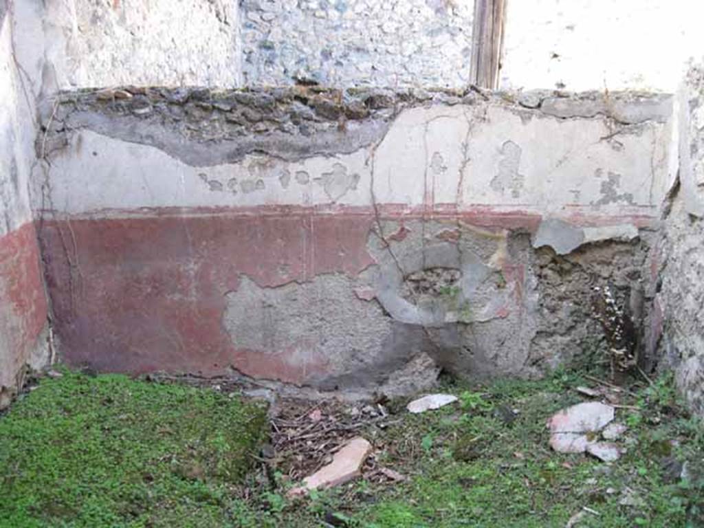 I.2.28 Pompeii. September 2010. North wall of room on south side of triclinium, with window onto garden area. Photo courtesy of Drew Baker.
According to Fiorelli, this room had access to a short underground passage for keeping provisions. See Pappalardo, U., 2001. La Descrizione di Pompei per Giuseppe Fiorelli (1875). Napoli: Massa Editore. (p.37)
According to Warscher, quoting Mau in Bull. Inst, 1874, p.250/51, she wrote –
“Il peristilio, situate piu alto dell atrio a causa del terreno inuguale, ha corridoi di 3 e 3 colonne sui lati S ed E, mentre verso N ed O confina con le case adiacenti (I.2.17; I.2.22; I.2.24).
Le colonne sono di mattoni e di stucco rozzo, color di carne fino all’altezza del muriciuolo che le congiunge, bianco di sopra.
La parte occidentale del portico meridionale, posteriormente soltanto, come ci fa testimonianza lo stucco delle colonne, coperto dal muro, ne fu separato e trasformata in una camera, che mediante una porta corrisponde colla camera a sinsitra del tablino, mentre verso N con una finestra larga, distante dal suolo m.1,52, si apre sul peristilio.
Sotto il pavimento di questa camera v’è un cavo, largo m. 0,98 + 0,67, profondo m. 1,32, rivestito di stucco e di sopra a metà coperto, mentre l’apertura che rimane evidentemente doveva chiudersi con un coperchio.
Sifatto cavo, il primo di questa sorta che si sia trovato a Pompei, serviva senza dubbio per conservare tutto ciò, cher si voleva difendere dal caldo, facendo così le veci d’una piccola cantina.
Sul lato meridionale del peristilio vi è ancora un armadio stretto, aperto verso O, ed il cui fondo viene formato dal muro occidentale della camera a destra dell’atrio, la quale sporge un poco nel peristilio”.