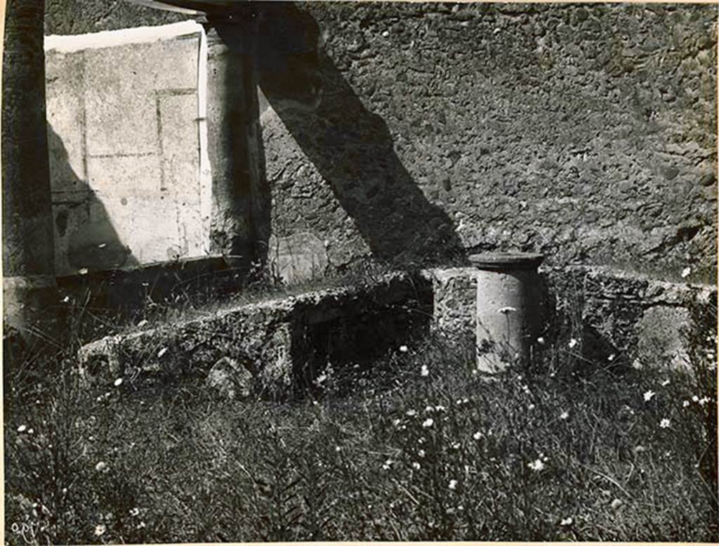 I.2.28 Pompeii. 1931. Looking west towards triclinium. See Warscher T., 1935. Codex Topographicus Pompeianus: Regio I.2. (no.54), Rome: DAIR, whose copyright it remains.
(According to Warscher, No.54, Triclinio nella parte occidentale del pseudo-peristilio (h).
La negative appartiene all’Istituto Arch. Germ. 1931; 2853.) Warscher wrote, quoting Bull. Inst.1874, p.251/52, that – “Il triclinio murato sta appoggiato al muro occidentale del peristilio, dimodochè verso la sera non vi poteva arrivare il sole, e, come quei ritrovati prima, è più alto verso la tavola, il cui posto è segnato da un sostegno rotondo, ove senza dubbio mettevasi la tavola di legno colle vivande. Più lungo degli altri è il letto a sinistra di chi sta avanti al triclinio, perchè a tavola si appoggiavano sul braccio sinistro, stendendo a destra la parte inferiore del corpo. Precisamente lo stesso si osserva nel triclinio della casa di Sallustio. Dalla parte interna di ciascuno dei letti sono quattro piccole nicchie, alte m. 0,24, larghe 0,19, profondo 0,20, più grande l’ultima del letto più lungo, separata dalle altre da una apertura del pozzo. Al triclinio si accedeva per un scalino alla estremità del letto settentrionale, dimodochè per arrivare al suo posto ciascuno doveva passare dietro ai posti degli altri. Ecco le misure del triclinio: letto meridionale, lunghezza esterna m.3,75, interna 2,35, larghezza 1,30; lunghezza interna del letto occidentale 1,37; letto settentrionale, lunghezza interna 1,30, esterna circa 2,50, larghezza 1,50. –
Aggiungo ancora che accanto allo scalino è un piccolo rialzo di materiale, che poteva servire di tavola, e che accanto all’estremità del letto più lungo sta un’ara fi tuffo, tonda, più grossa nella parte inferiore, con margine sporgente di sopra e di sotto, - finalmente che nel sostegno della tavola dalla parte di S si è fatto una specie di taglio verticale e piuttosto profondo, che non arriva fino alla superficie e di cui non ho saputo indovinare lo scopo”.