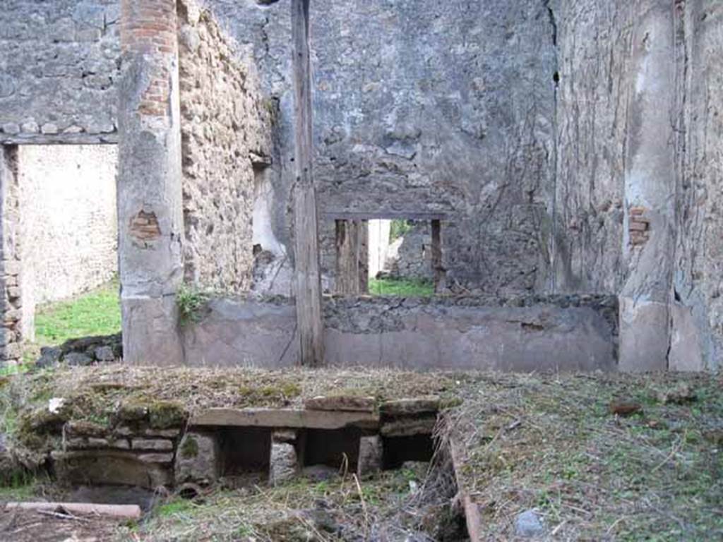 I.2.28 Pompeii. September 2010. Looking south across triclinium towards rear room with window, and doorway to tablinum (on left). Photo courtesy of Drew Baker.
According to Warscher, “Il triclinio occupa la parte opccidentale del pseudo-peristilio.
Si vedono quattro buchi rettangolari che illuminavano il sotterraneo; l’ingresso a questo ultimo è dalla stanza adiacente (a sinistra nella fotografia no.54 (stanza L)”.
According to Warscher, quoting Mau in Bull. Inst, 1874, p.250/51, she wrote –
“Il peristilio, situate più alto dell atrio a causa del terreno inuguale, ha corridoi di 3 e 3 colonne sui lati S ed E, mentre verso N ed O confina con le case adiacenti (I.2.17; I.2.22; I.2.24). Le colonne sono di mattoni e di stucco rozzo, color di carne fino all’altezza del muriciuolo che le congiunge, bianco di sopra. La parte occidentale del portico meridionale, posteriormente soltanto, come ci fa testimonianza lo stucco delle colonne, coperto dal muro, ne fu separato e trasformata in una camera, che mediante una porta corrisponde colla camera a sinistra del tablino, mentre verso N con una finestra larga, distante dal suolo m.1,52, si apre sul peristilio. Sotto il pavimento di questa camera v’è un cavo, largo m. 0,98 + 0,67, profondo m. 1,32, rivestito di stucco e di sopra a metà coperto, mentre l’apertura che rimane evidentemente doveva chiudersi con un coperchio. Sifatto cavo, il primo di questa sorta che si sia trovato a Pompei, serviva senza dubbio per conservare tutto ciò, che si voleva difendere dal caldo, facendo così le veci d’una piccola cantina. Sul lato meridionale del peristilio vi è ancora un armadio stretto, aperto verso O, ed il cui fondo viene formato dal muro occidentale della camera a destra dell’atrio, la quale sporge un poco nel peristilio”.
See Warscher T., 1935. Codex Topographicus Pompeianus: Regio I.2. Rome: DAIR, whose copyright it remains.
(translation: "The peristyle, situated higher than the atrium due to the uneven ground, had a walkway of 3 and 3 columns on the south and east sides, while towards the north and west it was bordered with the adjacent homes (I. 2.17; I. 2.22; I. 2.24). The columns were of brick and rough stucco, red-coloured up to a height of a wall that joined them, white above. As could be seen by the stucco of the columns covered by the wall, the western part of the south portico at the rear only, was separated and transformed into a room, that by means of a door joined with the room to the left of the tablinum, while towards the north, 1,52 m distance from ground, a large window opened onto the peristyle. Under the floor of this room there was a pit, 0,98m + 0.67 width, 1,32 m deep, faced with stucco and half covered above, while the opening that remained obviously would need to close with a lid. Such a pit, the first of its kind to be found at Pompeii, was undoubtedly to preserve everything, that you wanted to protect from the heat, thus making this the place of a small cellar. On the south side of the peristyle there was still a narrow cupboard, open towards the west, and whose base was formed by the west wall of the room to the right of the atrium, which protruded a little onto the peristyle ".)