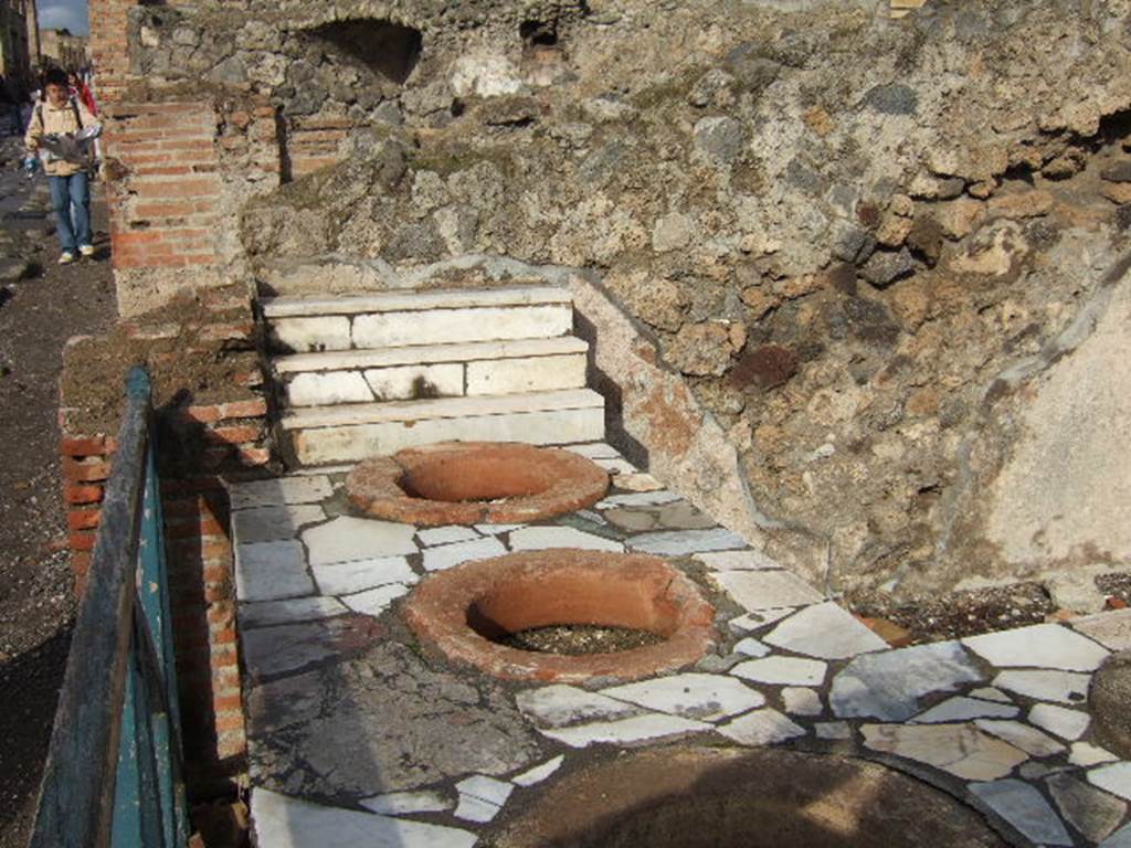I.3.2 Pompeii. December 2005.
Looking towards the north wall and counter, with four large terracotta dolia and display shelves. According to Boyce –
In the north wall is an arched niche (its condition too ruinous for measurement), its walls coated with white stucco.
See Boyce G. K., 1937. Corpus of the Lararia of Pompeii. Rome: MAAR 14. (p.23, no.18).