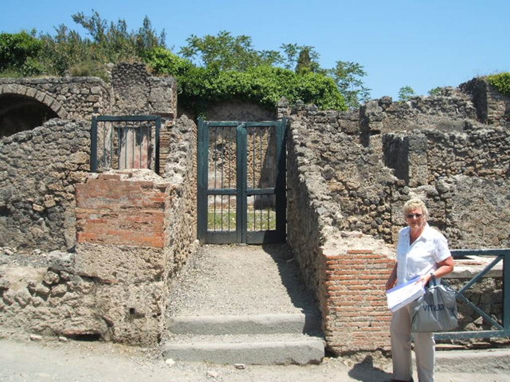 I.3.3 Pompeii. May 2005. Entrance on Via Stabiana. According to Warscher, quoting Bull. Inst, 1874, p. 183, she wrote –
Quanto alla pittura decorativa di questa casa, nella parte più bassa di essa tutte le pitture mostrano lo stile degli ultimi tempi di Pompei, coll’eccezione della camera a destra della scala.
Ed alla stessa epoca di quella camera, la terza cioè fra quelle pompeiane, se non m’inganno, appartiene tutto quello che sta intorno al peristilio. Ho parlato appunto di questa casa nel Giorn. d Sc. II, p.456. Chiara è l’identita delle stile riguardo la prima camera dal suo lato occidentale. Il resto delle camere è decorato in uno stile che può dirsi quello de’candelabri, perchè divide la parete in tre parti mediante candelabri molto sottili e svelti. E come accennai nel luogo citato, appunto le pitture di queste camere mediante certe piccole particularità non tanto facili a descriversi ci fanno riconoscere questo stile come affine e probabilmente contemporaneo a quello delle due camere menzionate. Ed allo stile di queste pare appartenesse anche la decorazione del peristilio stesso, benchè poco ne sia conservato.
Que’ cambiamenti adunque che, come sopra accennai, subì la casa in discorso, si rileva dalla stessa decorazione che non ebbero luogo negli ultimi tempi di Pompei, ma probabilmente prima del terramoto dell’a. 63 d.C.
See Warscher, T, 1935: Codex Topographicus Pompejanus, Regio I, 3: (dopo no. 11a), Rome, DAIR.