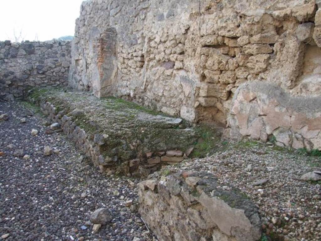 I.3.16 Pompeii. December 2007. West wall with remains of podium. This used to have two tubs at the south end. The boiler, the round gap in the centre of the picture, was used to heat a vessel.