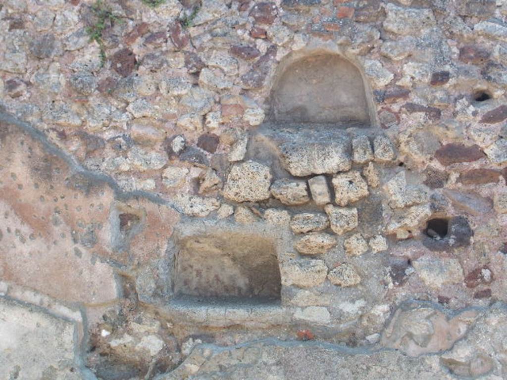 I.4.16 Pompeii. May 2005. Two niches on south wall. According to Boyce, either or both of these could have been lararia. The upper niche was arched and had its walls coated with red stucco. The lower rectangular niche had a back wall which curved from back to front. Its walls were coated with white stucco decorated with painted red dots, to represent flowers.
See Boyce G. K., 1937. Corpus of the Lararia of Pompeii. Rome: MAAR 14. (p.25)