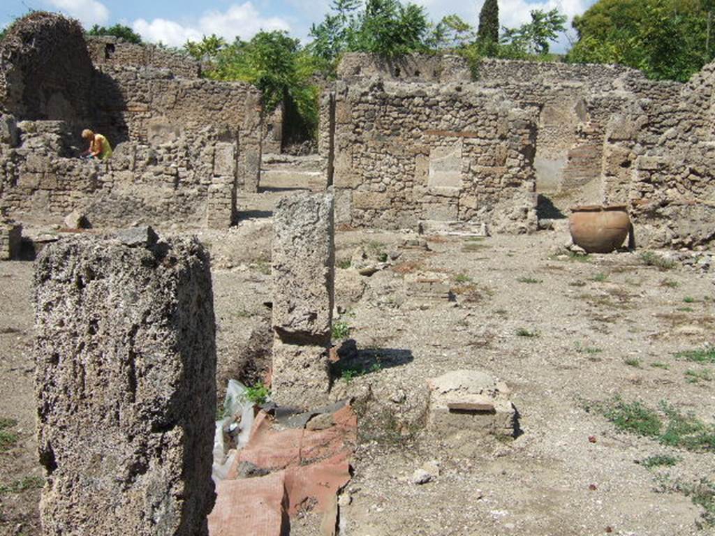 I.5.2 Pompeii. September 2005. Looking north along east side of peristyle.
According to Boyce, there was a ruined lararium in a room on the north-east side of the peristyle. It was a solid podium against the wall, with its three sides painted in imitation marble. There was a painted aedicula on the wall above it. See Boyce G. K., 1937. Corpus of the Lararia of Pompeii. Rome: MAAR 14. (p.25)