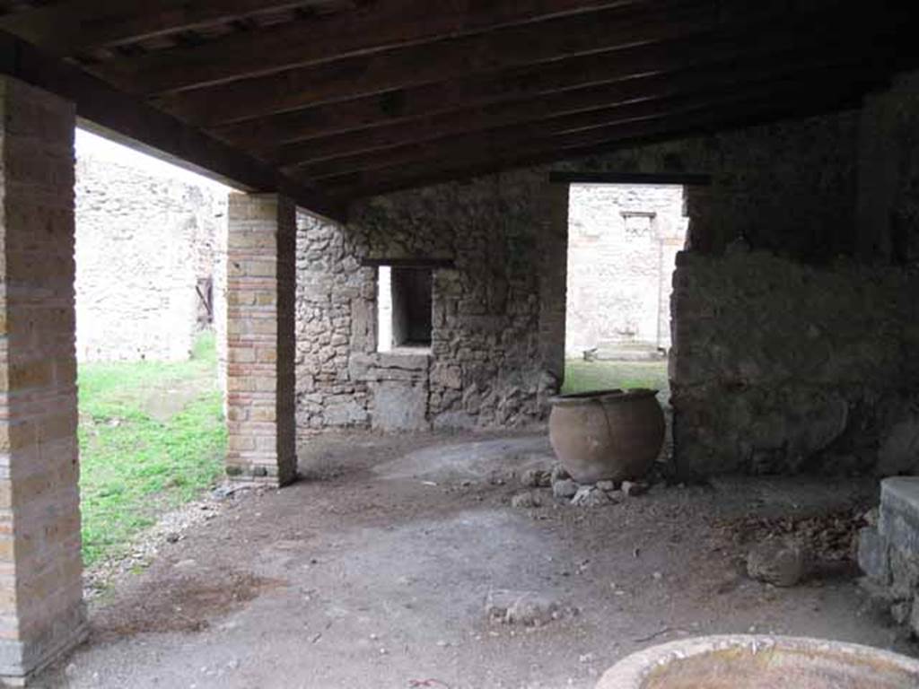 I.5.2 Pompeii. September 2010. Looking north along east portico towards doorway to two rooms leading to industrial area. The ruined podium of the lararium can be seen on the west, left side, of the doorway. Photo courtesy of Drew Baker.