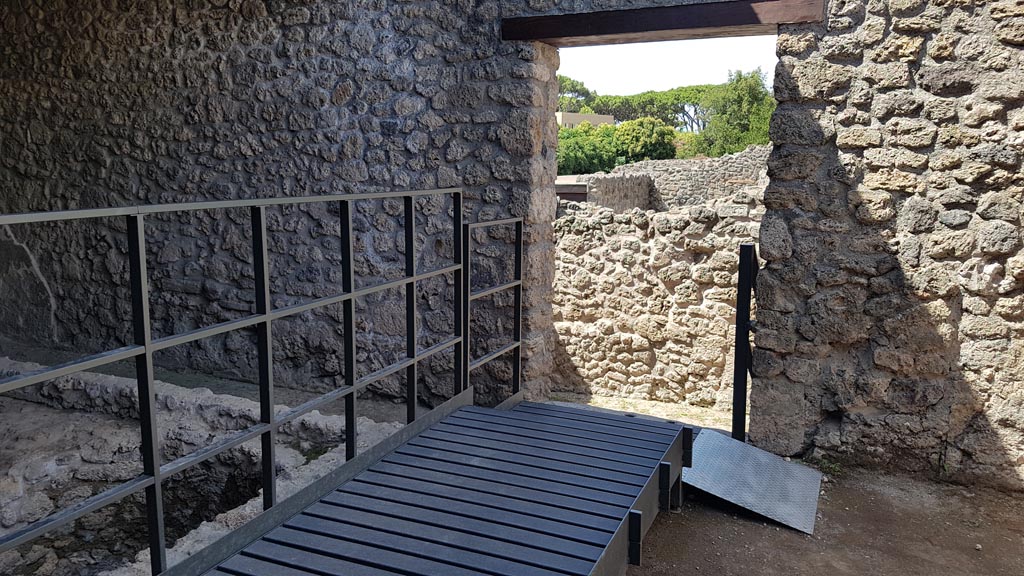 I.5.2 Pompeii. August 2023.
Looking west from industrial back room with fifteen vats towards doorway and steps down. Photo courtesy of Maribel Velasco.