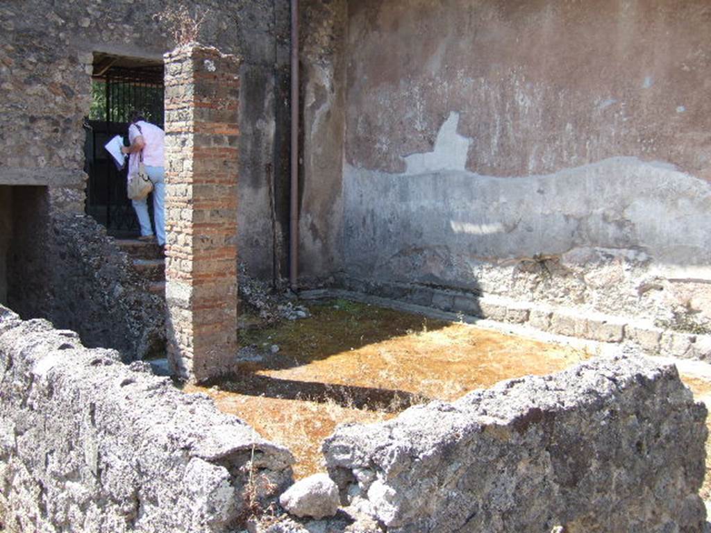 I.6.2 Pompeii. May 2006. Looking south-west across the small peristyle garden.
The garden was enclosed with a low wall on the north and east sides.  
The large brick pillar used to support the roof of the portico. 
Behind the pillar are the stairs leading up to the summer loggia with triclinium.  
See Jashemski, W. F., 1993. The Gardens of Pompeii, Volume II: Appendices. New York: Caratzas. (p. 34).


