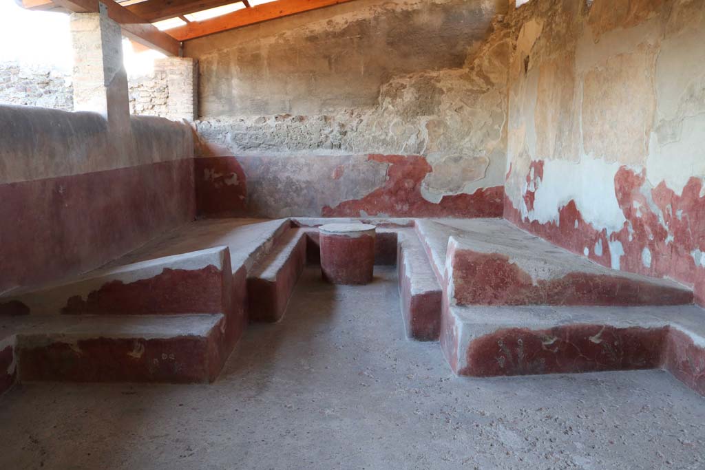 I.6.2 Pompeii. December 2018. Triclinium with table, against the west wall of the loggia.
The circular table, the couches and the benches, were all painted with motifs of plants and birds on a red background.
Photo courtesy of Aude Durand.