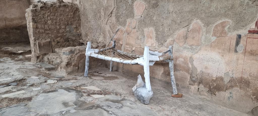 I.6.3 Pompeii. December 2023. Reconstruction (copy of the plaster-cast) of a slave’s cot against west wall. Photo courtesy of Miriam Colomer.
This reconstruction of a cot, a bed of the simplest known typology, was found in the suburban villa of Civita Giuliana, in the "slave room".
The simple bed, a sort of camp bed, consisting of a wooden frame with leather straps at the corners to fasten the various parts.
To this was tied a net of ropes on which the blanket rested.
