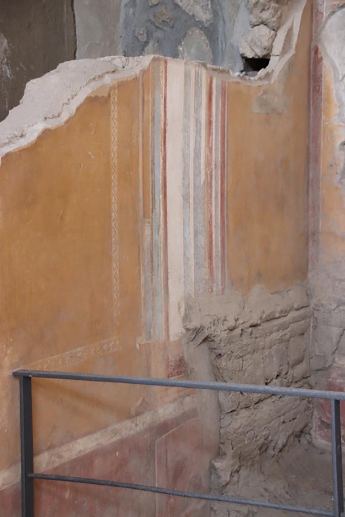 I.6.4 Pompeii. October 2022.
Room 4, detail from north wall at east end. Photo courtesy of Klaus Heese.
This shows part of the remaining “carved double row of framed rectangles” from the wooden bed, still visible in the ash.