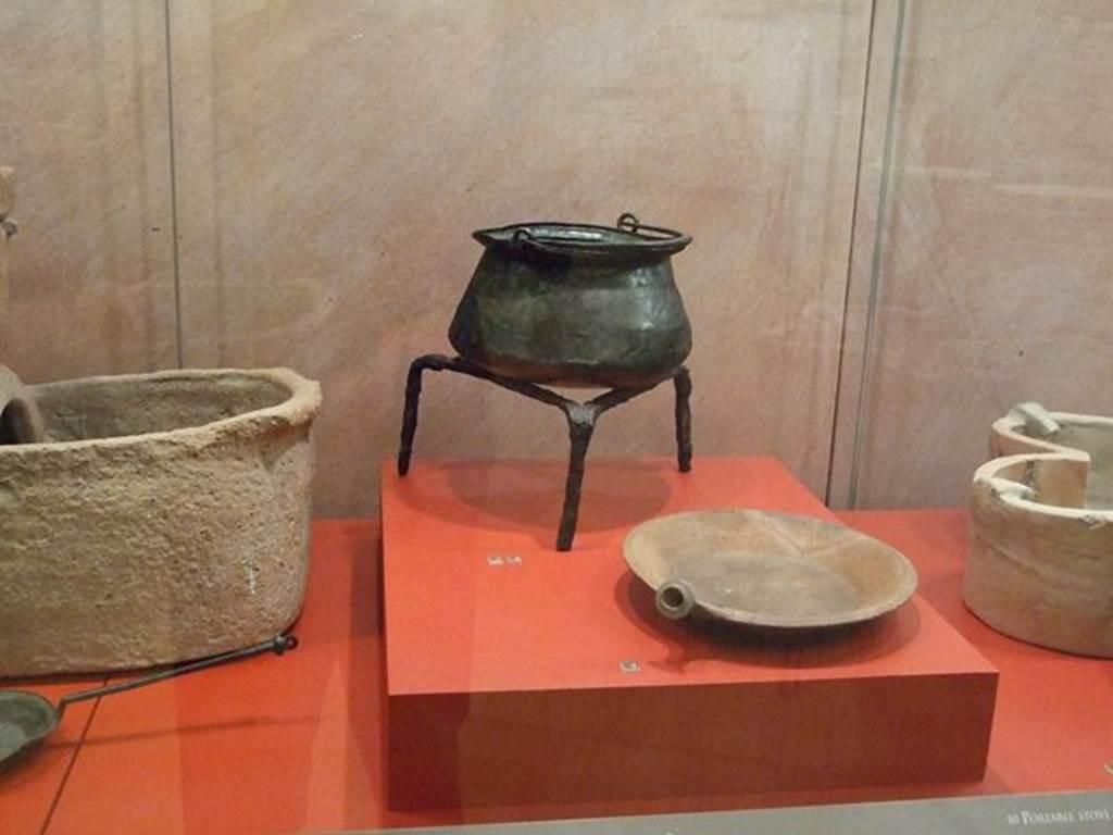 I.6.7 Pompeii. Bronze Caccabus or shallow cooking pot (at rear on tripod). SAP 4916.
Photographed at “A Day in Pompeii” exhibition at Melbourne Museum. September 2009.