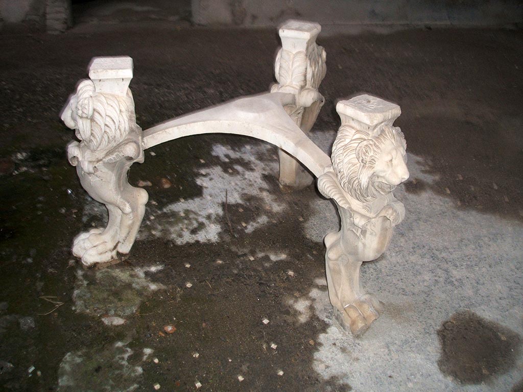 I.6.11 Pompeii. December 2004. Atrium. Marble tripod table legs with lion heads and paws. Inventory number 3921.
This house was named the Casa di P. Casca Longus from the inscription on the top of these table legs.
They were found in garden of House I.6.8-9 and moved to I.6.11 by the excavators.
See Carratelli, G. P., 1990-2003. Pompei: Pitture e Mosaici: Vol. I. Roma: Istituto della enciclopedia italiana. (p. 369).
According to Allison, this name is unsubstantiated, see http://www.stoa.org/projects/ph/house?id=3.