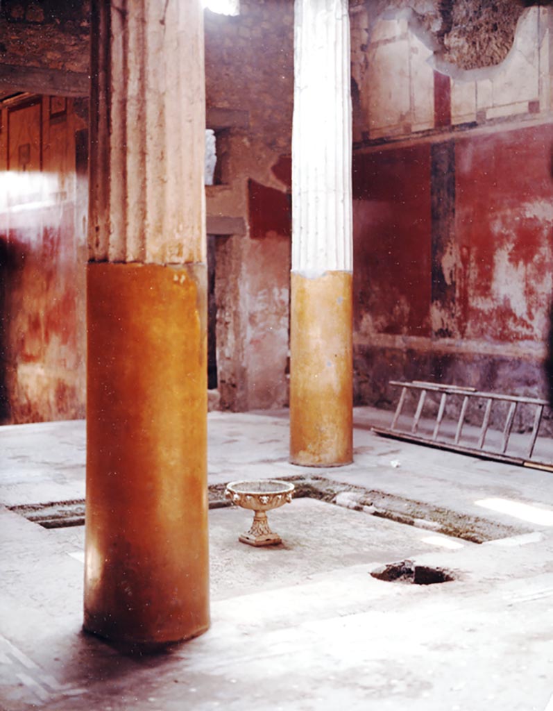 I.6.15 Pompeii, 1980 (pre-earthquake).
Room 4, looking south-west across impluvium in tetrastyle atrium, towards labrum fountain with animal masks, later stolen. Today there is only a hole left in the impluvium floor.
Photo courtesy of Espen B. Andersson, who has written a scientific article especially on this fountain.
See E. B. Andersson, Metamorphoses in Water, in Latomus, 50 (3), 1991, pp.544-562. “
(The article can be read on Academia or ResearchGate.)