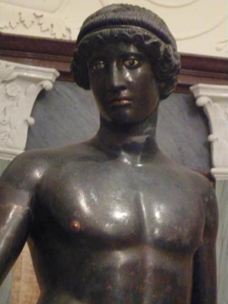 I.7.11 Pompeii. 2010. Front view of bronze statue of the ephebo from south side of atrium near tablinum.
The lifelike eyes were inlaid with corneas of white glass paste, cut to receive irises of a different colour now lost.
Photo courtesy of Buzz Ferebee.