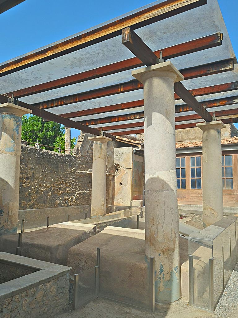 I.7.12 Pompeii. September 2024.
Looking north-west across triclinium in garden towards west wall and north portico.
Photo courtesy of Giuseppe Ciaramella.