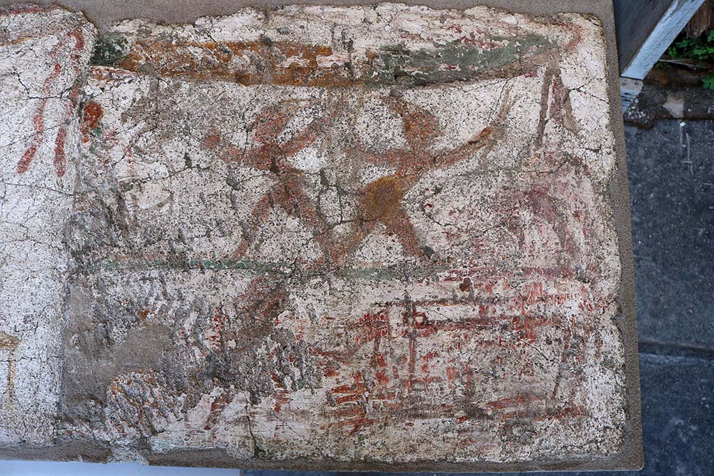 I.8.10 Pompeii. December 2018. Entrance façade painting. 
Mercury with a group of men attired in costumes resembling those of the later Neapolitan Punch and Judy puppets.
This led Della Corte to name this as the Hospitium dei Pulcinella.
PAP inventory number 45622.

According to Fröhlich, 
The figures are dark brown, reddish and light red, the dividing line between the two zones is green, the garland at the top of the picture is green and yellow.

The centre of the upper part of the picture is taken up by two dancing figures, each dressed in an apron and a pointed hat, who stride apart with wide steps, bending their upper bodies forward, spreading their arms wide and holding crossed sticks in each hand. On the left edge of the image is a white-robed figure with a donkey's head, on the right edge a horse or an ox, of which only the hind legs have survived. 

In the lower part of the picture, a small figure with a disproportionately large head appears to the right of a table on which a vessel is standing. On the right, a frame stands on four thin legs, from which the legs seem to hang down, perhaps a ferculum.

See Fröhlich, T., 1991. Lararien und Fassadenbilder in den Vesuvstädten. Mainz: von Zabern. (F5, p.307).
