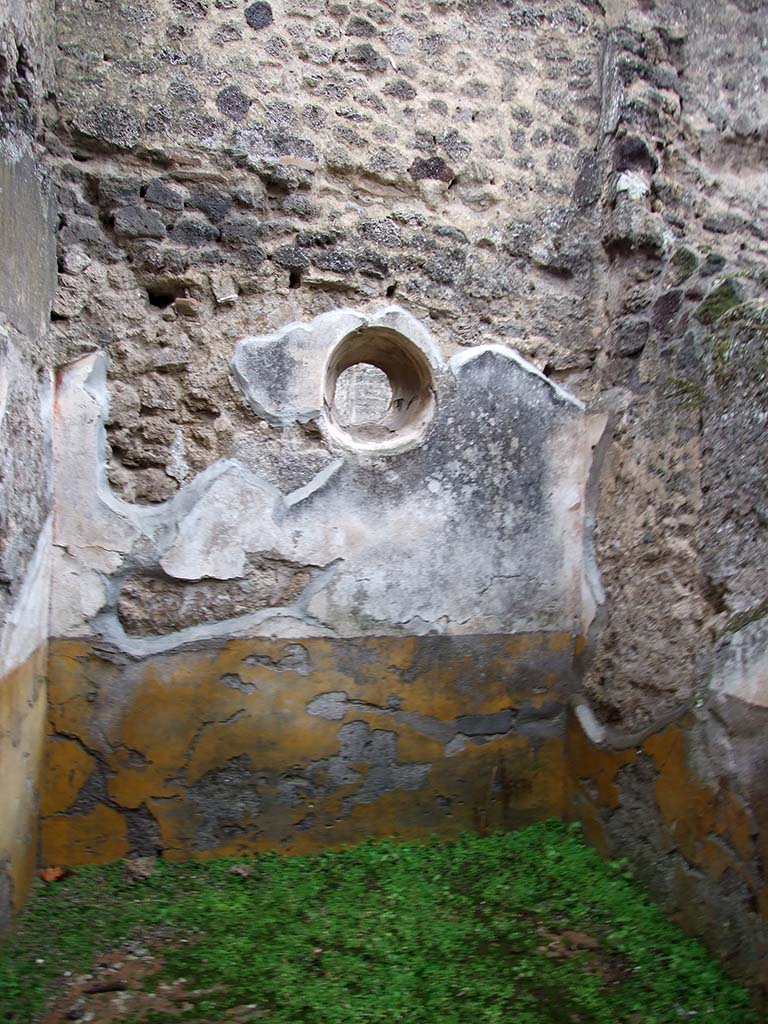 I.8.14 Pompeii. December 2007. Room 5, east wall of cubiculum with circular window. 
The high zoccolo was yellow, and the middle zone of the wall was white showing vignettes with “carpet borders” in the panels separated by compartments painted with golden candelabra. 
See/Vedi Carratelli, G. P., 1990-2003. Pompei: Pitture e Mosaici: Vol. I. Roma: Istituto della enciclopedia italiana, p. 838.

