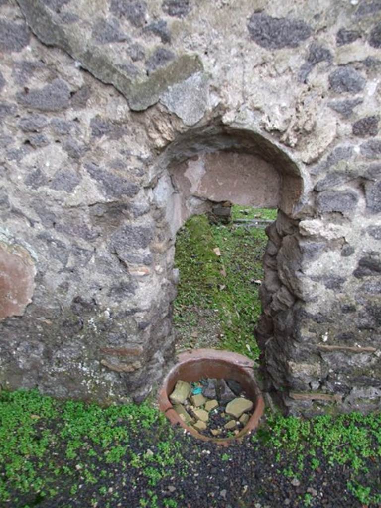 I.8.16 Pompeii.
Looking west through a hole in the wall from I.8.14, into the uncovered area, described as having a kitchen podium, and the channel to convey the waters from the adjoining house at I.8.14.