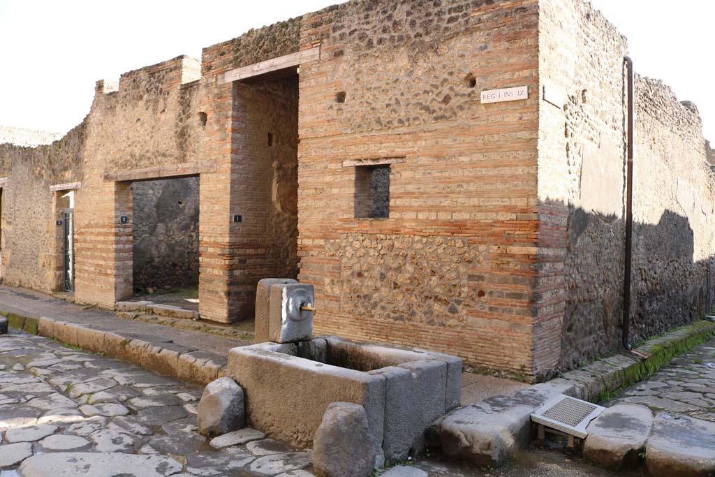 I.9.1 Pompeii, December 2018. 
Looking south-east on Via dell�Abbondanza towards doorway at the rear of the fountain. Photo courtesy of Aude Durand.
