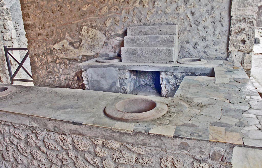 I.9.4 Pompeii. October 2001. Display shelving and two embedded dolia in counter against west wall. Photo courtesy of Peter Woods.