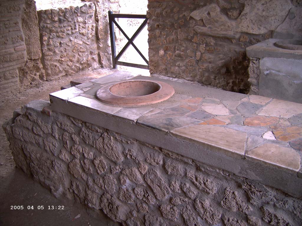 I.9.4 Pompeii. April 2005. East side of counter, with marble top and embedded dolium with hearth, on left.
Photo courtesy of Klaus Heese.