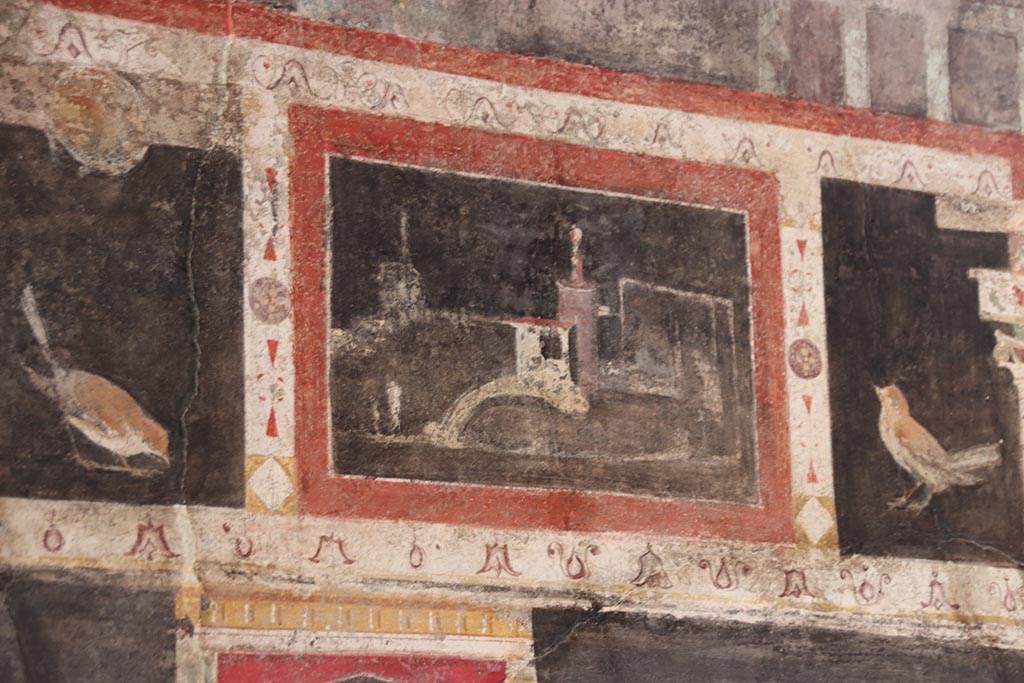 I.9.5 Pompeii. October 2024.
Room 10, triclinium, detail from upper centre of west wall on south side of central painting. Photo courtesy of Klaus Heese.