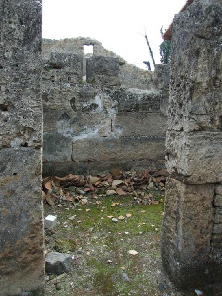 I.9.12 Pompeii. March 2009. Room 2, doorway to room on west side of entrance.
According to Fulford, when re-examined in 1995-6, it was found that this room had been left almost completely unexcavated, and had lapilli coming out of its doorway.
Originally, the walls of the room had been decorated with plain white plaster, and there was the possible existence of a staircase against the south wall. In 79AD, it was being used as a stable for one mule. Found in the north-west corner, was its skeleton. Two iron rings were discovered close to its head, which may have indicated that it had been tethered. Resting against one back leg, and pinned down by the other, was the skeleton of a dog. Found beneath the mule were the remains of a rectangular wooden trough or manger built against the north wall. This was recognised by voids in the lapilli and volcanic ash. Also found were the broken remains of the lower part of an amphora, perhaps holding water for the animals.
See Fulford, M. and Wallace-Hadrill, A: Rivista di Studi Pompeiani, VII, 1995-6, The House of Amarantus: an interim report on Survey and Excavations in 1995-96. (p.77-113).