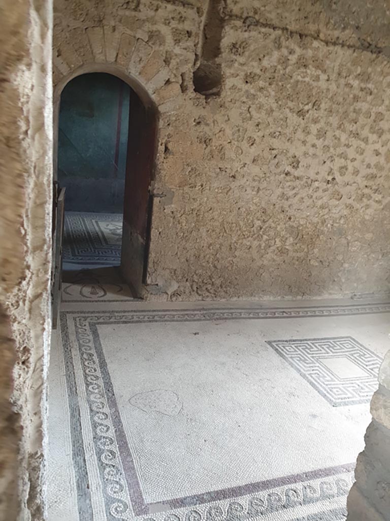 I.10.4 Pompeii. August 2023.
Room 47, looking south through doorway across flooring towards arched doorway into caldarium.
Photo courtesy of Maribel Velasco.