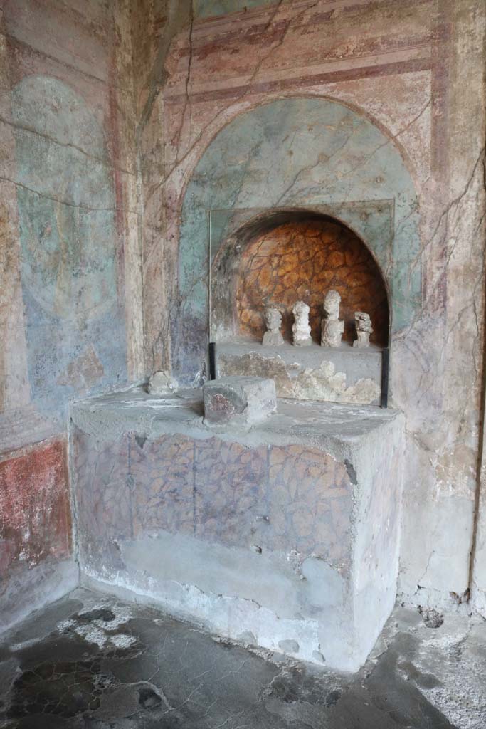 I.10.4 Pompeii. December 2018.
Alcove 25, altar to household gods against west wall. Photo courtesy of Aude Durand.
The busts are plaster cast taken from the cavities left by the original wooden busts.
These were imagines maiorum, ancestor images, and were accompanied a statuette of a sitting youth, identified as a lar (protective household god).