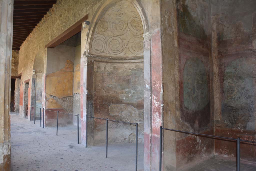 I.10.4 Pompeii. September 2019. Looking towards south side of south portico, from south-west corner.
On the right is Alcove 25 (Sacrarium), followed by Alcove 24, 23, and 22 and doorway to 21, in south-east corner.
Alcove 24 has a domed top decorated with stucco, underneath which is a painting of Venus and cherubs in a temple.
Alcove 23 has the painting of the seated poet Menander.
Alcove 22 also has a domed top decorated with stucco, underneath which is a painting of Diana and Acteon.
Room 21 has a mosaic emblema of satyr and maenad in the centre of the mosaic floor.
Foto Annette Haug, ERC Grant 681269 DÉCOR.