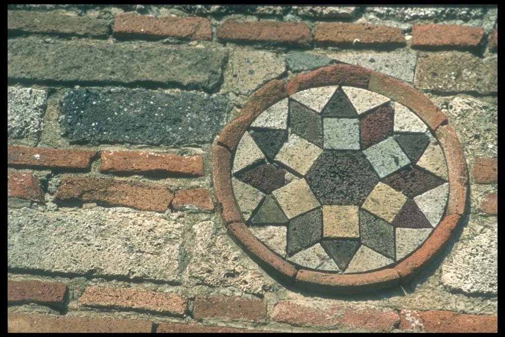 I.10.9 Pompeii. Coloured terracotta decorated circular plaque on north side of entrance.
Photographed 1970-79 by Günther Einhorn, picture courtesy of his son Ralf Einhorn.