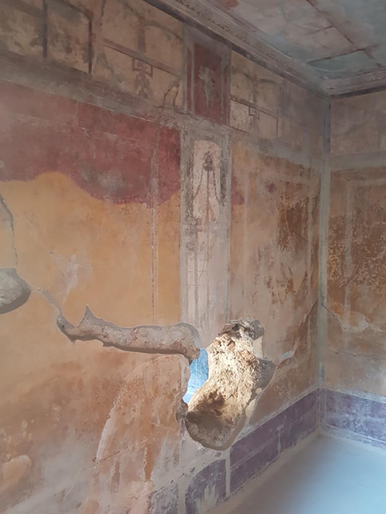 I.10.11 Pompeii. October 2022. Room 13, looking east along north wall.
The fact that the red painted walls have changed to yellow/orange is taken as a sign of intense heat/burning.
Photo courtesy of Klaus Heese.