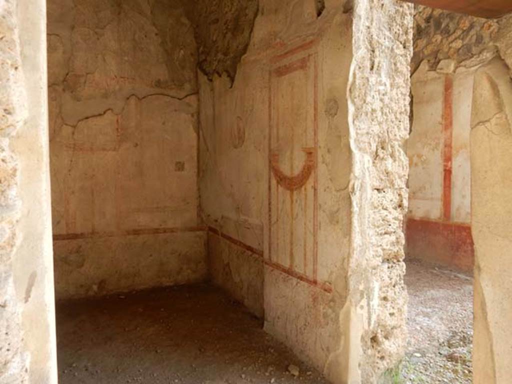 I.11.1 Pompeii. May 2015. South wall of the cubiculum. Photo courtesy of Buzz Ferebee. “The room to the east of the thermopolium, (room b) and communicating with it, was a cubiculum with rather neglected decorations of the IV Style, where only a few fragments of the barrelled ceiling could be recovered. On the eastern side was the recess for the bed and, in the cocciopesto floor, a central decoration of a chessboard in diamond shapes, made with minute white marble tesserae. In the centre of the largest panels of the walls were three medallions of 0.28m diam. In the south wall, the head of Diana with diadem facing front, with bow raised high in the left hand, and quiver behind the right shoulder, and the other two from the north wall were of the head of Bacchus, crowned with vine leaves facing front, and with slender staff on the right shoulder, and of nude Apollo in threequarters looking right, with his lyre held between his hands. In the smaller space (east wall), flying towards the centre, two naked Cupids, one holding a long lamp and a tray, and the other something like an umbrella.”
See Notizie degli Scavi, 1913, p.249-50.
(L’ambiente ad est del termopolio, e con esso comunicante (b), era un cubicolo con decorazioni piuttosto trascurate di IV stile, del cui soffitto a botte soltanto pochi frammenti si sono potuto recuperare. Nel lato orientale era il rincasso per il letto e, nel pavimento di cocciopesto, una scacchiera centrale a reticella di rombi, fatta con tesserae minute di marmo bianco. Al centro dei maggiori riquadri delle pareti, tre medaglioni di 0.28m di diam. esibiscono l’uno (parete sud) il busto di Diana, di fronte, diademata, con arco nella sinistra levata in alto e turcasso dietro la spalla destra, e gli altri due (parete nord) i busti di Bacco di fronte, coronato di foglie di vite e con esile tirso sulla spalla destra, e di Apollo, in terza a destra, nudo, con la cetra stretta fra le mani.
Negli spazi minori (parete est) convergono, volando verso il centro, due Eroti nudi, reggenti l’uno una lunga face e un vassoio, e l’altro come un ombrello.)