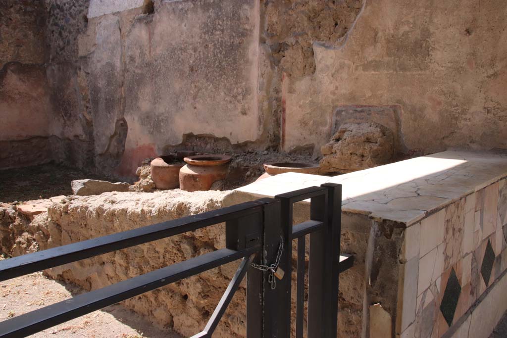 1.11.1 Pompeii. September 2019.
Looking towards west side with remains of four urns and shelves for displaying drinking vessels. Photo courtesy of Klaus Heese.