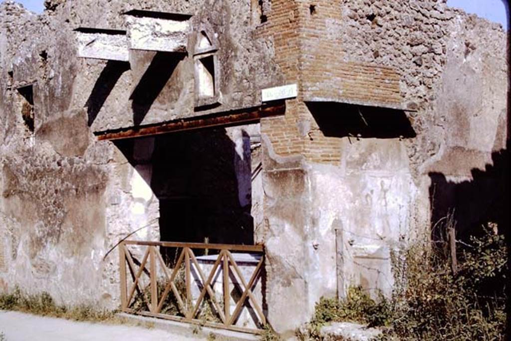 I.11.1 Pompeii. 1968. Entrance on Via dell’Abbondanza. Photo by Stanley A. Jashemski. On the right, in the side vicolo, a street altar can be seen.
Source: The Wilhelmina and Stanley A. Jashemski archive in the University of Maryland Library, Special Collections (See collection page) and made available under the Creative Commons Attribution-Non Commercial License v.4. See Licence and use details. J68f0371
According to Della Corte, “Reg. II, ins.1, on high between doorways 1 and 2, a window was found (0.80m wide x 1.20m high), protected by a grating which remains in its place in reasonable state of preservation; beyond the described window and continuing towards the east, and it seems placed above doorways 2 and 3, a large roof was found a little knocked down from its original position, about 6m. long (but the eastern extremity was not yet discovered), and protruding by just over 2m. At the rear of the wall of the façade of doorway 1, definitely in their place were the remains of the basins/tubs mentioned last month, putting all the fragments of one of them back into its place with its bottom. "
See Notizie degli Scavi, 1913, p.220.
(Reg. II, ins. 1. Tra I vani 1 e 2 in alto, si e scoperta una finestra (larga 0.80m. alta 1.20m) protetta da inferriata che resta tuttora al suo posto in discreto stato di conservazione; oltre la descritta finestra, procedende sempre verso oriente, e quindi imposta sul vani 2 e 3 come pare, si era rinvenuta, di poco abbattuta dalla sua originaria posizione, una grande tettoia, lunga per ora (non se ne era ancora scoperta l’extremita orientale) 6m, e sporgente per poco piu di m.2. A tergo del muro di facciata del vano 1 si sono definitivamente assicurati al posto loro gli avanzi delle vasche accennate il mese scorso, rimettendo a posto interamente i frammenti di una di esse col relativo fondo.”)