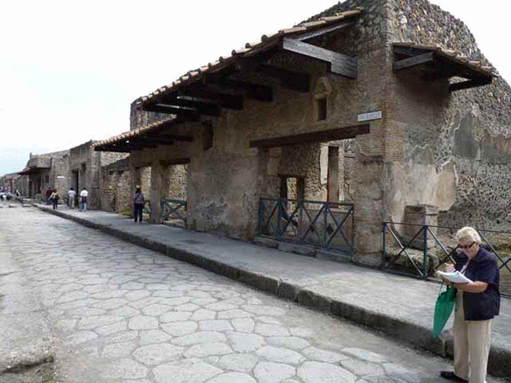 Via dell’Abbondanza, south side. May 2010. Looking east from near unnamed vicolo towards I.11. I.11.1 is the doorway on the right of the photo. Above the doorways of I.11.2, left of centre, and I.11.3, left of I.11.2, windows can be seen in the upper floor.
According to Della Corte, “Reg. II, ins.1, on high between doorways 1 and 2, a window was found (0.80m wide x 1.20m high), protected by a grating which remains in its place in reasonable state of preservation; beyond the described window and continuing towards the east, and it seems placed above doorways 2 and 3, a large roof was found a little knocked down from its original position, about 6m. long (but the eastern extremity has not yet been discovered), and protruding by just over 2m. At the rear of the wall of the façade of doorway 1, definitely in their place were the remains of the basins/tubs mentioned last month, putting all the fragments of one of them back into its place with its bottom. " See Notizie degli Scavi, 1913, p.220.
(Reg. II, ins. 1. Tra i vani 1 e 2 in alto, si e scoperta una finestra (larga 0.80m. alta 1.20m) protetta da inferriata che resta tuttora al suo posto in discreto stato di conservazione; oltre la descritta finestra, procedende sempre verso oriente, e quindi imposta sul vani 2 e 3 come pare, si era rinvenuta, di poco abbattuta dalla sua originaria posizione, una grande tettoia, lunga per ora (non se ne era ancora scoperta l’extremita orientale) 6m, e sporgente per poco piu di m.2. A tergo del muro di facciata del vano 1 si sono definitivamente assicurati al posto loro gli avanzi delle vasche accennate il mese scorso, rimettendo a posto interamente i frammenti di una di esse col relativo fondo.”)