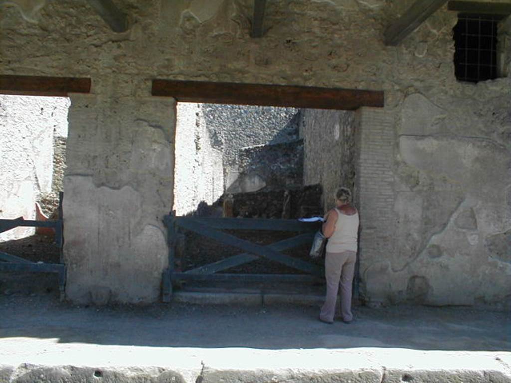 I.11.2 Pompeii. May 2005. Entrance doorway, looking south.
According to Della Corte, “Reg. II, ins.1, on high between doorways 1 and 2, a window was found (0.80m wide x 1.20m high), protected by a grating which remains in its place in reasonable state of preservation; beyond the described window and continuing towards the east, and it seems placed above doorways 2 and 3, a large roof was found a little knocked down from its original position, about 6m. long (but the eastern extremity was not yet discovered), and protruding by just over 2m. At the rear of the wall of the façade of doorway 1, definitely in their place were the remains of the basins/tubs mentioned last month, putting all the fragments of one of them back into its place with its bottom. " See Notizie degli Scavi, 1913, p.220.
(Reg. II, ins. 1. Tra i vani 1 e 2 in alto, si e scoperta una finestra (larga 0.80m. alta 1.20m) protetta da inferriata che resta tuttora al suo posto in discreto stato di conservazione; oltre la descritta finestra, procedende sempre verso oriente, e quindi imposta sul vani 2 e 3 come pare, si era rinvenuta, di poco abbattuta dalla sua originaria posizione, una grande tettoia, lunga per ora (non se ne era ancora scoperta l’extremita orientale) 6m, e sporgente per poco piu di m.2. A tergo del muro di facciata del vano 1 si sono definitivamente assicurati al posto loro gli avanzi delle vasche accennate il mese scorso, rimettendo a posto interamente i frammenti di una di esse col relativo fondo.”)