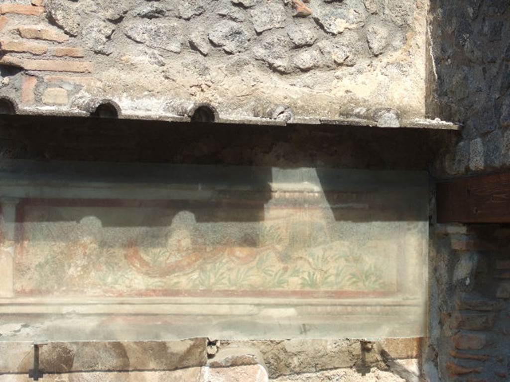 I.11.11 Pompeii. September 2005. Lararium on north wall of thermopolium.
A stucco border surrounding a serpent moving left to a round altar. In the background are green plants with red flowers. See Fröhlich, T., 1991. Lararien und Fassadenbilder in den Vesuvstädten. Mainz: von Zabern. (L21, T:14,1:24,2).