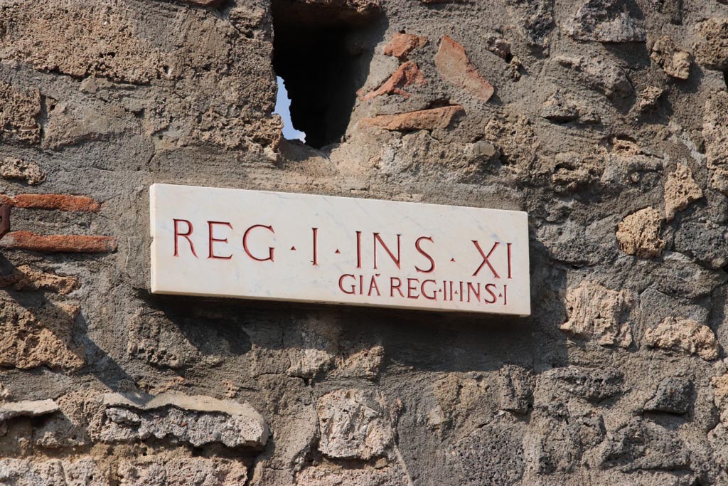 I.11.11 Pompeii. October 2022.
Identification plate on west side of entrance doorway, originally known as Reg. II. Insula 1, now Reg. I. Insula XI. Photo courtesy of Klaus Heese.