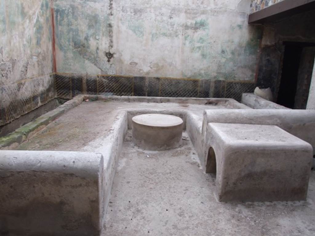 I.11.16 Pompeii. December 2007. Room 6, triclinium with round and square tables.
According to Jashemski, “The courtyard (a) at the rear of the hospitium (excavated in 1960) was separated from the roofed passageway on the south by a low wall 0.62m high. Most of the courtyard was occupied by a masonry triclinium (l. medius 3.80m, l. summus 2.73m, l. imus 4.15m, table 0.80m in diameter). There was a hearth at the end of the l. summus, which measured 0.77 x 0.90m. A garden painting on the north and east walls of the courtyard gave the area the appearance of a garden.”
See Jashemski, W. F., 1993. The Gardens of Pompeii, Volume II: Appendices. New York: Caratzas. (p.53, and p.325, and figs 375-6)