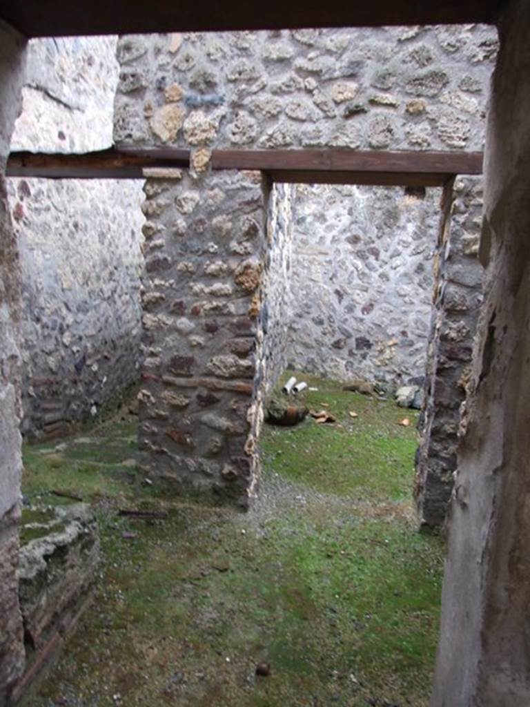 I.11.16 Pompeii. December 2007. Room 10, the kitchen, looking south towards doorways of rooms 11 and 12. According to Packer, room 12 may have been a dormitory for slaves.
There were no traces of stucco on the walls of rooms 10 or 11, but in room 12 the stucco was plain white. The room on the upper floor above room 12 may have been painted yellow.