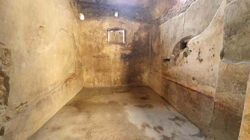 I.11.16 Pompeii. July 2021. Room 5, room in south-west corner of bar-room/atrium, looking west from doorway.
Foto Annette Haug, ERC Grant 681269 DÉCOR.
According to Packer, the room received its light from a window in the west wall which was later closed and converted into a rectangular niche.
As cuttings in the plaster of the west wall showed, the original ceiling was a false vault with a crown 3.05m above the floor.
Packer included the note: “RDP report that this room was under excavation on July 14 1960. Some of the more important items found in it include:
an ovoidal bronze situla, a bronze patera, a silver spiral form ring, the bronze disk of a mirror, part of a lock, a terracotta lamp and an Arretine plate”.
See Packer, J: Inns at Pompeii: a short survey, in Cronache Pompeiane IV-1978 (p.18-24, with note on page 20).