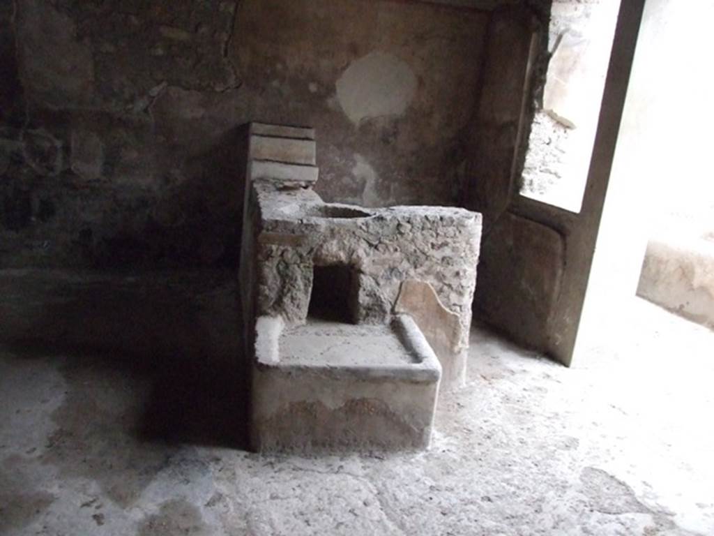 I.11.16 Pompeii. December 2007. Room 1, looking north at bar counter. According to Packer, against the north wall were three small shelves probably used for the storage of cups, glasses and beakers. Originally there were two containers embedded into the counter, but only the smallest remains in situ. In the larger opening would have been a bronze or lead container, supported by five brick projections so as to leave space below for coals, an arrangement that was used to heat liquids. The coals were raked underneath the container through a rectangular opening reached from the low hearth attached to the south side of the counter. The counter, shelves and hearth were all stuccoed.