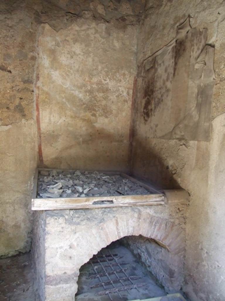 I.12.8 Pompeii. March 2009. Room 10, north-west corner of kitchen with lararium. On the north wall can just be seen some cloth, which has adhered to the lararium and damaged it.
It used to show one serpent approaching a round altar from the right. See Giacobello, F., 2008. Larari Pompeiani: Iconografia e culto dei Lari in ambito domestico. Milano: LED Edizioni. (p.152-3). According to Curtis, the lararium painting covering two walls above the oven in the kitchen was beautiful but badly-deteriorated. Painted on the north wall was a large single serpent near an altar. On the altar were sacrificial gifts, such as pine cones.
There may have been another scene beneath the serpent, but the wall was too badly damaged to verify this. See Curtis, R.I: The Garum shop at Pompeii, In Cronache Pompeiane, V,1979, (p.20-1)