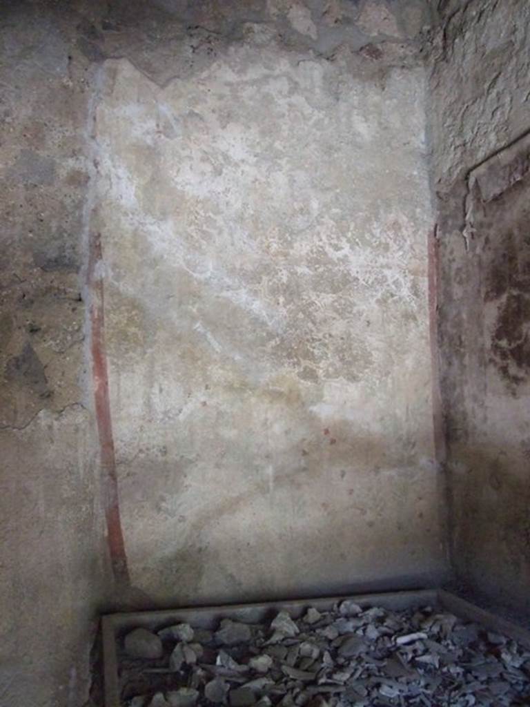 I.12.8 Pompeii. March 2009. Room 10, west wall. Painted on the upper west wall was a round altar with a genius flanked by two lares with a rhyton and a patera. On the lower west wall was a garland with painted plants and birds underneath. See Fröhlich, T., 1991. Lararien und Fassadenbilder in den Vesuvstädten. Mainz: von Zabern. (L26, T:26,1).
According to Giacobello, the legs of the lares used to be visible at the top of the wall, but only their booted legs as their upper parts were destroyed. See Giacobello, F., 2008. Larari Pompeiani: Iconografia e culto dei Lari in ambito domestico. Milano: LED Edizioni. (p.152-3).
According to Curtis, on the west wall was a painting in two parts, both in a bad state of preservation. In the upper part appeared the genius of the family, or owner, sacrificing on an altar which was on his right. Two possible lares were shown, one on the left side of the altar, and the other to the right of the figure near the altar. The lower panel presented a garden scene including three birds, one perched on a branch, one standing on the ground, and one in flight. See Curtis, R.I: The Garum shop at Pompeii, In Cronache Pompeiane, V,1979, (p.20-1)