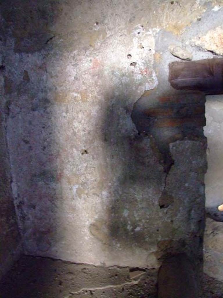 I.12.11 Pompeii. March 2009. Lararium painting on west wall of kitchen, above hearth.
According to Giacobello, the lararium painting in the south-west corner of the kitchen was on the walls that against which the bench was placed.
It was not very preserved, but showed garlands in red/yellow/green, with underneath them a trace of sky blue.
See Giacobello, F., 2008. Larari Pompeiani: Iconografia e culto dei Lari in ambito domestico. Milano: LED Edizioni. (p. 154).