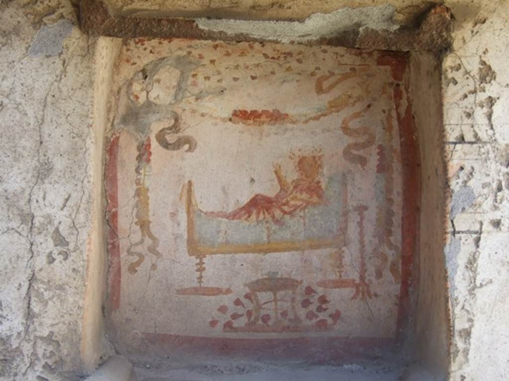I.14.7 Pompeii. March 2009. West wall of garden area.
Niche lararium with painting of a god in a long white robe lying on a couch.
The right hand holds a branch and the left holds a patera.
To the right is a golden candelabrum.
At the front is a three legged table with a bowl of fruit. Above is a garland.
See Fröhlich, T., 1991. Lararien und Fassadenbilder in den Vesuvstädten. Mainz: von Zabern. (L34, T:29,3)