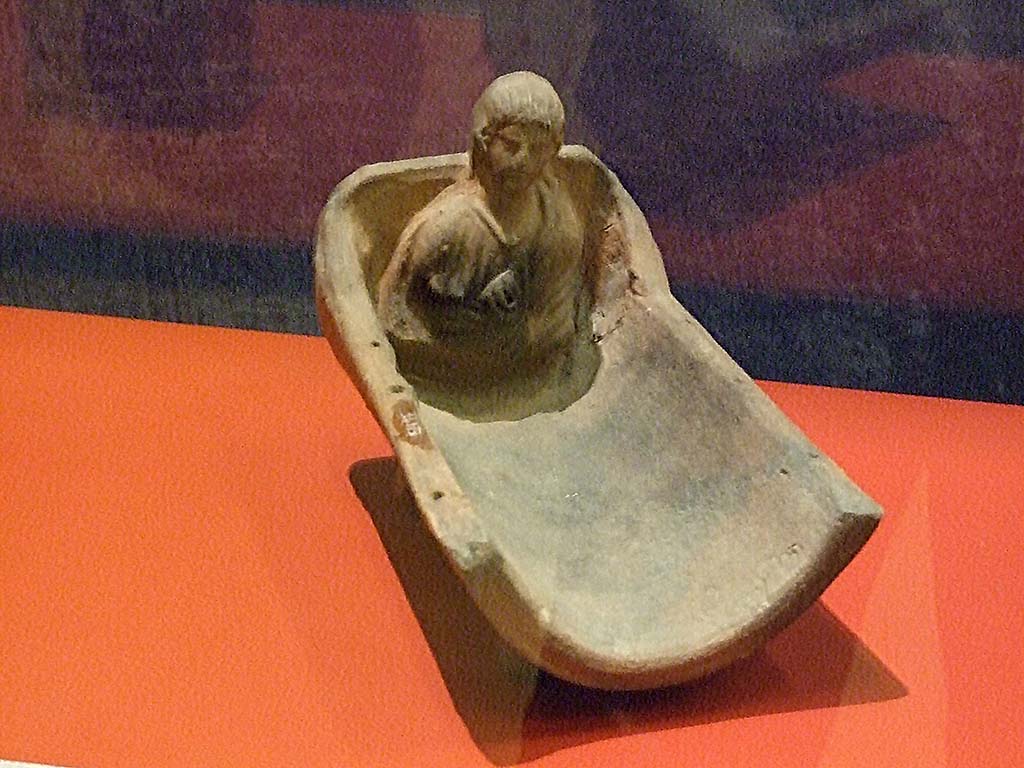 I.14.15 Pompeii. Cradle-shaped terracotta perfume burner with bust of a young boy with amulet around his neck. SAP 34973.
Photographed at “A Day in Pompeii” exhibition at Melbourne Museum. September 2009.