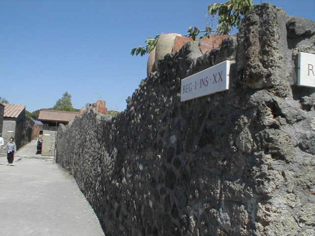 Via della Palestra, looking east along exterior north wall of I.20.5. May 2005.
According to Jashemski, the broken amphorae inserted in the top of this wall would have protected the garden from thieves.
The large phallus carved in Sarno limestone, painted red, and inserted on the west end of the outside of the north wall gave protection from evil.
See Jashemski, W. F., 1993. The Gardens of Pompeii, Volume II: Appendices. New York: Caratzas. (p. 67).